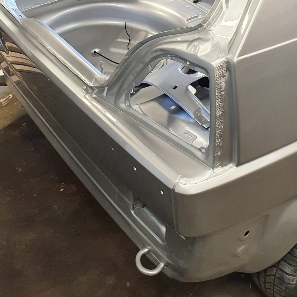 Close-up van een nieuw gelast en zilvergrijs gespoten achterlichtframe en bumperbalk ivm de restauratie van deze VW Golf Mk2.
